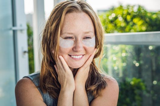 Portrait of Beauty Red-haired woman with eye patches showing an effect of perfect skin. Spa Girl.