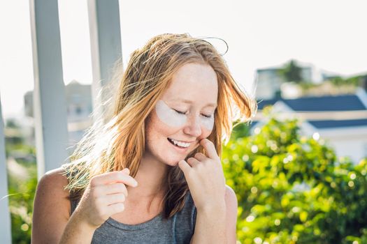 Portrait of Beauty Red-haired woman with eye patches showing an effect of perfect skin. Spa Girl.