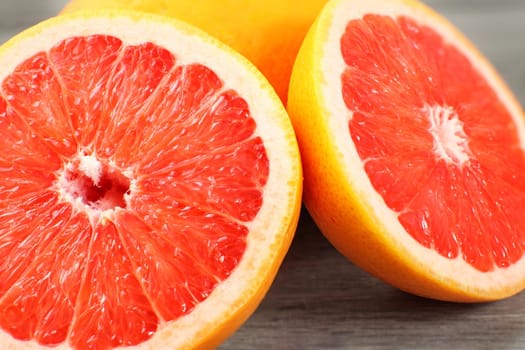 Closeup of pink grapefruit cut in half, on gray wood desk.