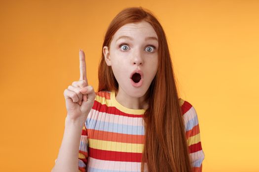 Wow got excellent idea. Excited shocked redhead girl open mouth raise index finger eureka gesture stare camera thrilled adding suggestion have plan think-up solution, standing orange background.