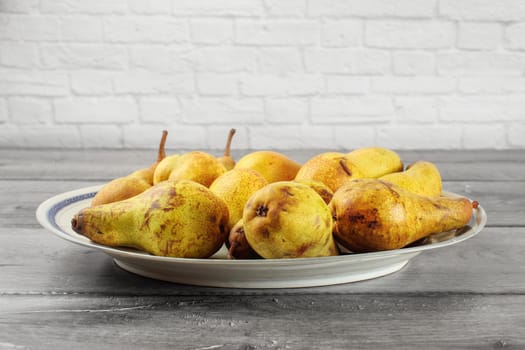 Plate full of pears on gray wood desk.