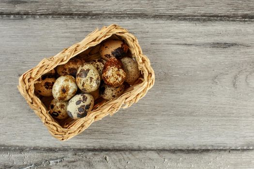 Table top view of quail eggs placed in small rectangular basket.