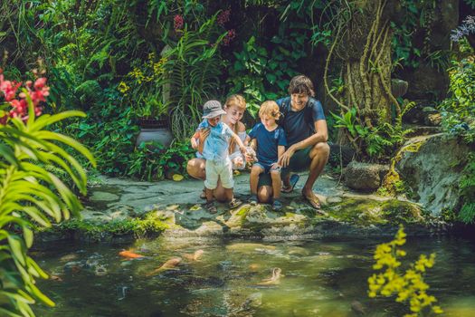 happy family feeding colorful Catfish in tropical pond.