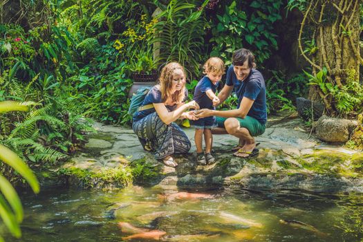 happy family feeding colorful Catfish in tropical pond.