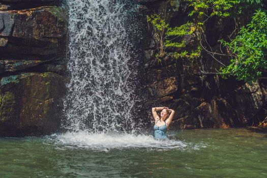 A young woman is standing in a waterfall.