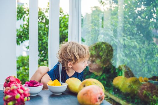 Little cute boy eating mango on the terrace.