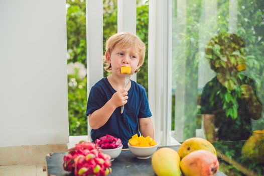 Little cute boy eating mango on the terrace.