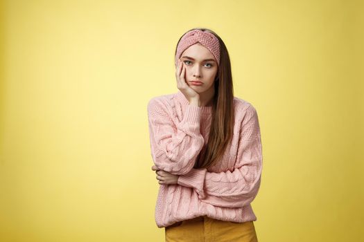 How boring. Indifferent upset gloomy girl missing party feeling bored leaning on palm reluctant, sad looking careless at camera visiting uninteresting lecture, suffering boredom over yellow wall.