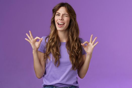 Got it relax everything perfect. Relaxed carefree curly girl winking cheeky smiling cunning show okay ok ring sign assure all good stand satisfied accepting great choice approving purple background.