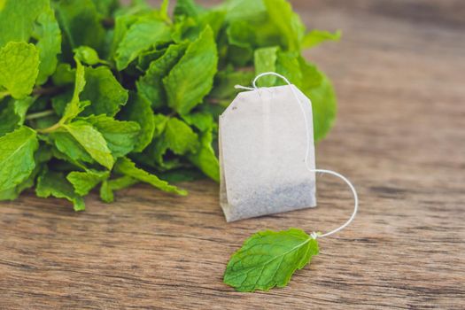 Tea bags on wooden background with fresh melissa, mint. Tea with mint concept.