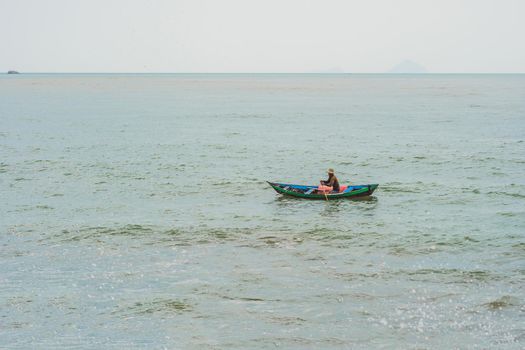 Vietnamese fisherman swims in a boat over the raging sea.