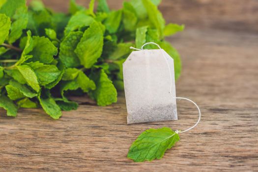 Tea bags on wooden background with fresh melissa, mint. Tea with mint concept.