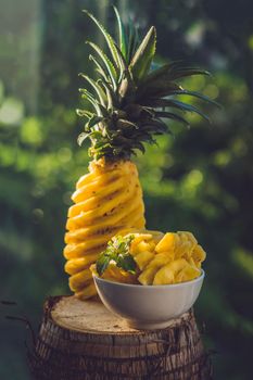 Pineapple and pineapple slices on a background of greenery.