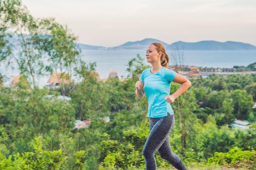 A sportive young woman is engaged in running against the sea.