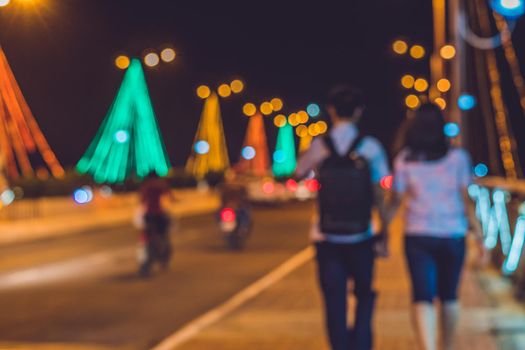 Young couple on the background Busy traffic on a bridge at night. Glowing bridge supports. Blurred focus.