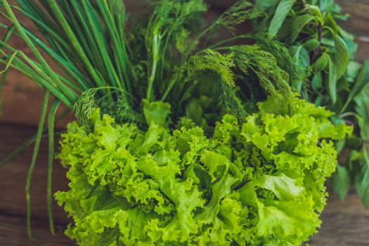 A variety of fresh organic herbs on an old wooden background.