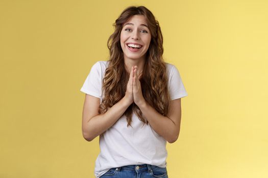 Cheerful cute hopeful girl clingy begging look camera optimistic faithfully press palms together pray supplication gesture asking favour pleading apology positive lucky mood yellow background.