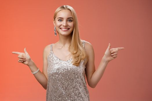 Waist-up shot energized cheerful blond european girl in silver glittering dress pointing sideways left right smiling amused showing lots variants variety opportunities make choice which better.