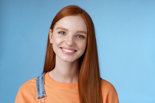 Cheerful lively redhead caucasian girl smiling happily look camera kind sincere friendly talking have perfect summer holidays talking friends standing blue background joyful. Copy space