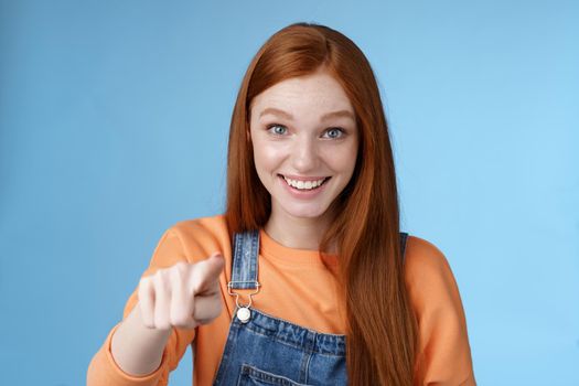 Impressed surprised young cute girl pointing camera amazed wide eyes astonished look questioned unsure congratulating friend made successful effort, standing blue background glad. Emotions concept