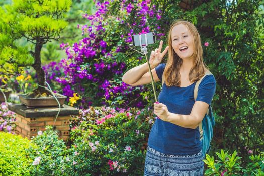 young beautiful girl doing selfie mobile phone in the park on summer day.