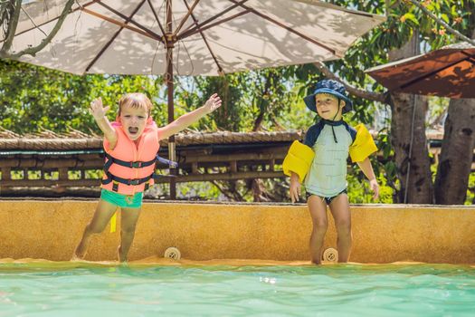 two young boys friends jumping in the pool.