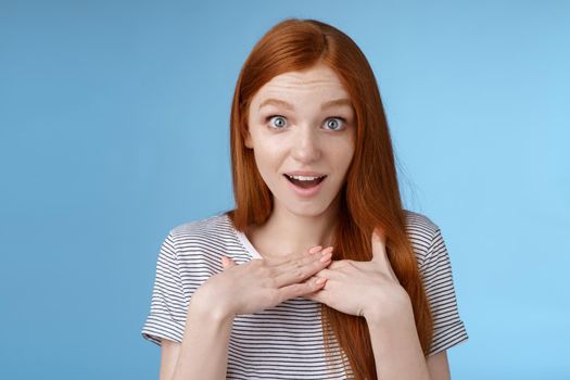 Amazed surprised young sincere redhead girl look astonished questioned gasping impressed press palms chest wide eyes stunned receive pleasant impressive gift stare gratitude touched feelings.