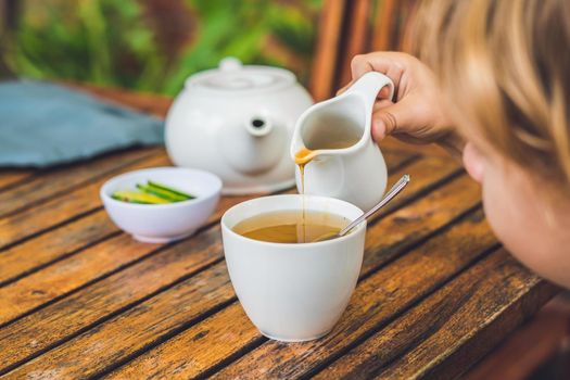 Happy nice boy pours honey into the tea in summer green garden. Portrait. outdoor.