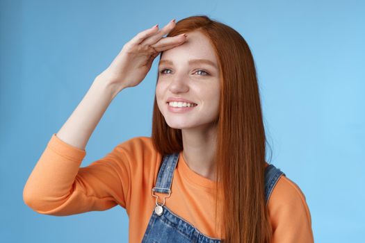 Girl look far distance turn left hold hand forehead cover eyes hot sunlight smiling delighted watching were ball fall peer afar joyfully squinting get closer, standing blue background.