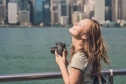 Young woman taking photos of victoria harbor in Hong Kong, China.