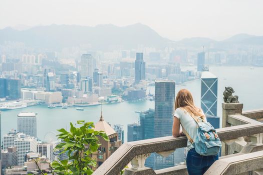 Young woman traveler at the peak of Victoria against the backdrop of Hong Kong.