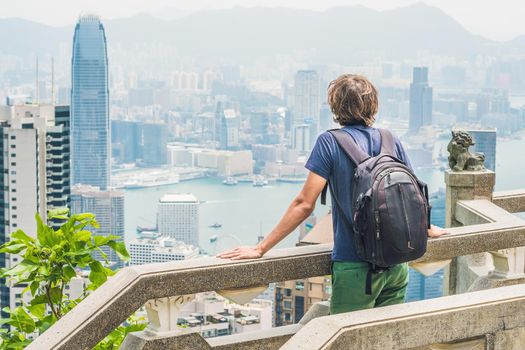 Young man traveler at the peak of Victoria against the backdrop of Hong Kong.
