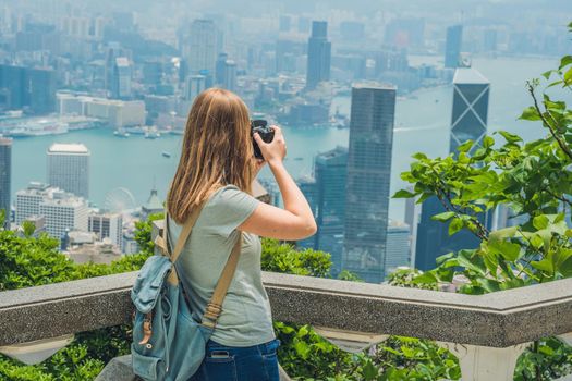 Young woman taking photos of victoria harbor in Hong Kong, China.
