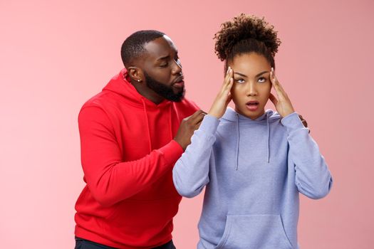 Man apologizing girlfriend behind back touching shoulder comforting girl feel pressured irritated fed up lying hear boyfriend sorry arguing standing bothered pink background, couple fighting.