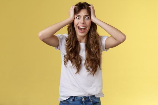 Girl screaming panic. Troubled distressed anxious woman see huge mess terrified feel sorrow shouting shocked grab head hopeless problem terrible situation yelling shook stunned yellow background.