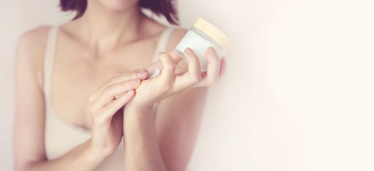 Young female hands hold a jar of moisturizing cream to maintain health, softness of the skin, the woman takes care of her health and beauty.