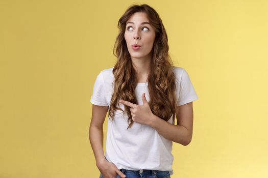 Hmm interesting wow. Curious silly cute pretty woman long curly hairstyle folding lips admiration tempting try out new menu look pointing upper left corner fascinated intrigued yellow background.