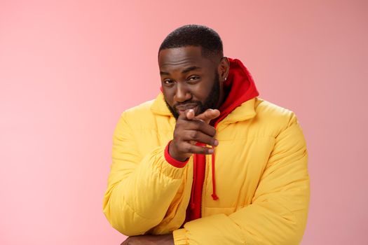 Guy suspecting you pointing camera index finger squinting disbelief unsure, standing pink background asking question look doubtful hesitant, express distrust wear yellow jacket red hoodie.