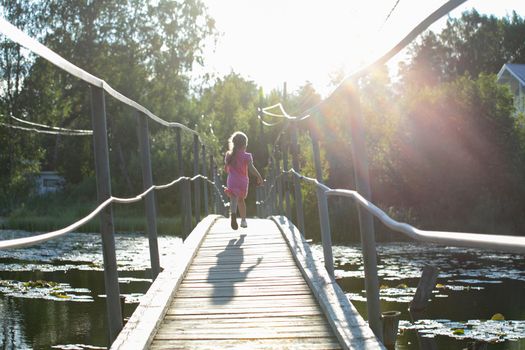 Happy Little Girl crossing suspension bridge. High quality photo