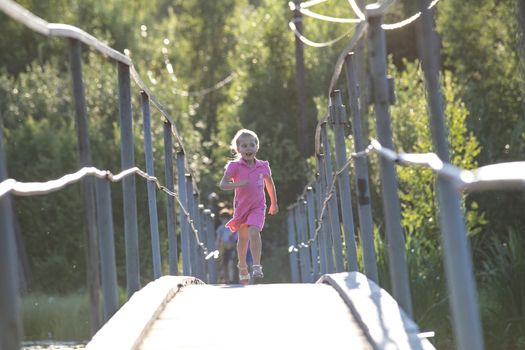 Happy Little Girl crossing suspension bridge. High quality photo