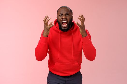 Guy hates subway. Irritated hungry mad bearded african-american man yelling squeez fists frowning grimacing shouting losing temper furiously staring camera go crazy insane, standing pink background.