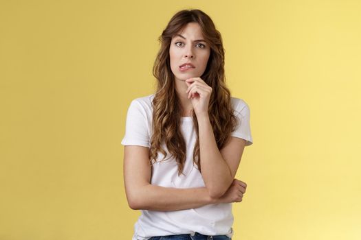 Troublesome situation give sec think. Intrigued thoughtful focused smart girlfriend thinking touch chin bite lip look camera focused pondering choice making decision solve problem yellow background.