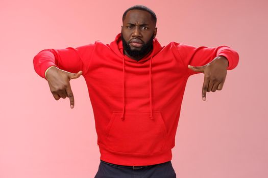 Questioned displeased pissed handsome serious-looking athletic black guy bearded frowning look perplexed wondered freak out pointing down waiting explanation, standing frustrated pink background.