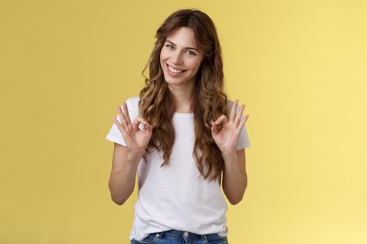 Not bad for newbie. Cunning good-looking young creative female colleague guarantee excellent result show okay ok approval gesture, assure friend everything perfect stand yellow background assertive.
