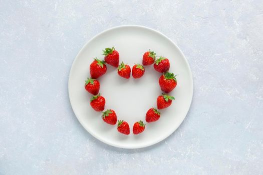 white plate with strawberries in a heart shape, concept of Valentine's Day, top view