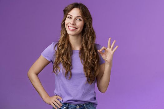 Confident professional girl not scared difficult task assure everything okay smiling broadly self-assured pose hold hand hip show ok ring sign grinning accepting agree good terms purple background. Lifestyle.
