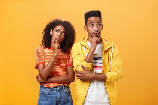 Two brains better than one. Thoughtful couple of african american friends in stylish urban outfit standing in thinker pose looking up determined and focused making up plan how spend evening. Relationship concept