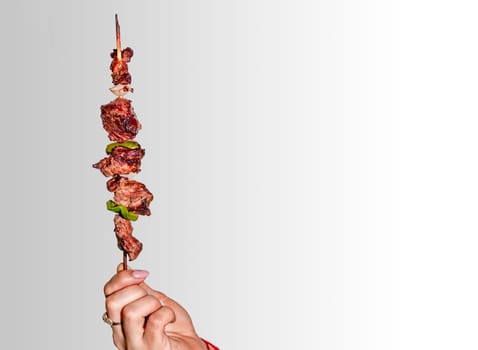 A hand holding a roast beef skewer, Hand holding roast beef skewer on white background