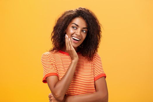 Cute creative and feminine stylish african american young female in striped t-shirt leaning head on palm gazing left with curious and adorable expression delightfully listening interesting story. Lifestyle.