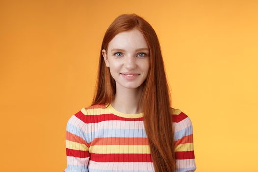 Lifestyle. Pleasant friendly-looking confident smart redhead female student aim success smiling self-assured express lucky positive upbeat mood casually hang out orange background listening amusing story.